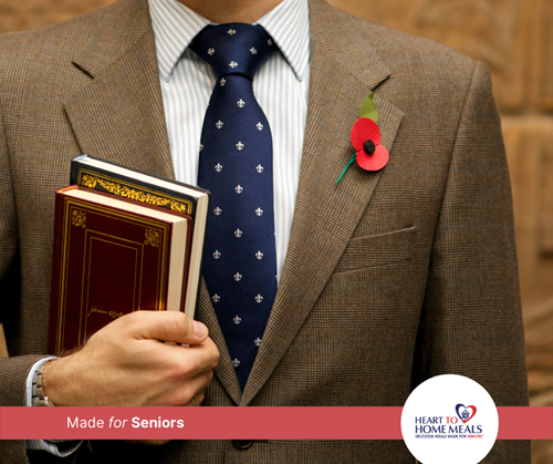 gentleman in suit wearing a red poppy and holding books